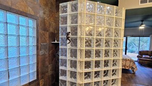 Un espace de douche avec des parois en blocs de verre, un sol carrelé et une fenêtre en verre dépoli.