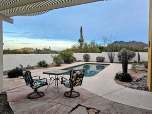 A pool area with two chairs, a pergola, and a view of mountains and cacti. - Authentic Desert Vibes 3-bedroom house with pool & AC in charming Cave Creek (Cave Creek)