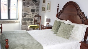 Un letto rifatto con cura, con una coperta a motivi decorativi, una testata in legno e diversi cuscini.