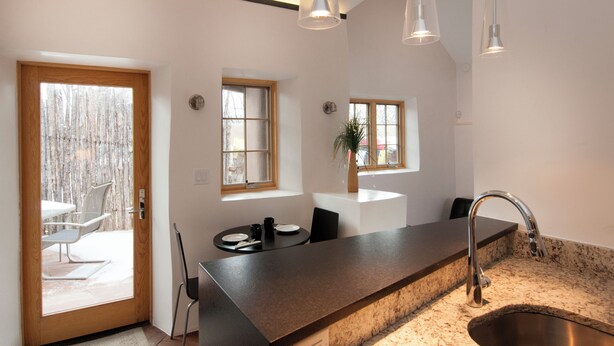 A modern kitchen with a granite countertop, stainless steel sink, and pendant lighting.