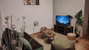 Ein Wohnzimmer mit einer Couch, einem Couchtisch, einem Fernseher, Dekoration und einer Pflanze.