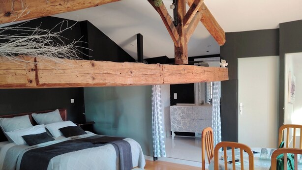 Ein Schlafzimmer mit Schlafkoje, Holzboden, Esstisch mit Stühlen und einer Küchenzeile im Hintergrund.