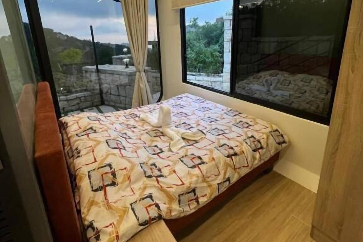 A compact bedroom with a bed, a window, and a view of the outdoors.
