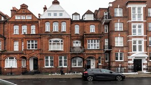 A row of red brick townhouses with white window frames and a black car parked in front. - Two Bedroom Flat - Next to West Kensington Station - Pass the Keys (London)