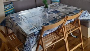 Una habitación acogedora con un ventanal grande, una mesa estampada, sillas de madera y un banco empotrado con cojines.