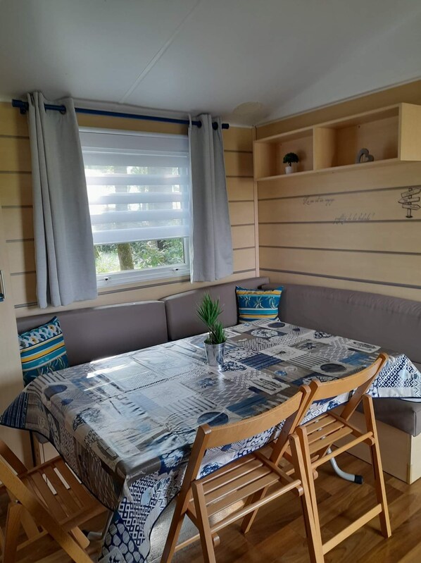 Una habitación acogedora con un ventanal grande, una mesa estampada, sillas de madera y un banco empotrado con cojines.