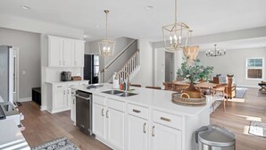 A modern kitchen with white cabinetry, stainless steel appliances, and pendant lighting. - Spacious 6-bedroom house near Pinehurst (Southern Pines)