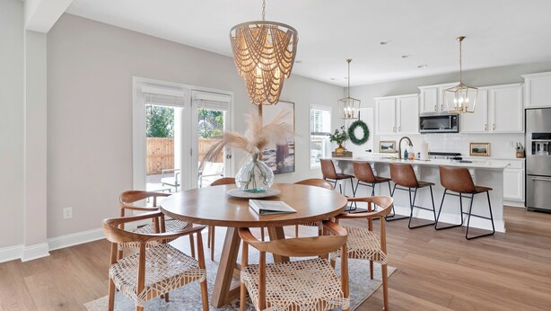 A modern kitchen with white cabinets, stainless steel appliances, and a central island with bar stools. - Spacious 6-bedroom house near Pinehurst (Southern Pines)