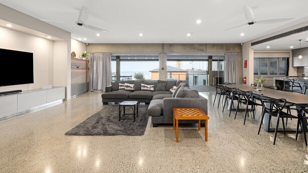 A modern living room with a sofa, coffee table, and dining area with chairs. - Striking Luxury Home With Garden & BBQ (Margate)