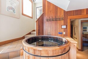 Eine Holzwanne in einem Raum mit einer Holzwand und einer Treppe.
