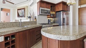 A kitchen with granite countertops, wooden cabinets, a microwave, stove, and refrigerator. - Two Bedroom Ocean View (Bajos de Chila)