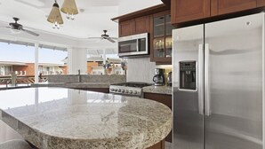 A kitchen with granite countertops, a stainless steel refrigerator, a microwave, and a gas stove. - Two Bedroom Ocean View (Bajos de Chila)