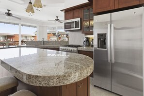 A kitchen with granite countertops, a stainless steel refrigerator, a microwave, and a gas stove. - Two Bedroom Ocean View (Bajos de Chila)