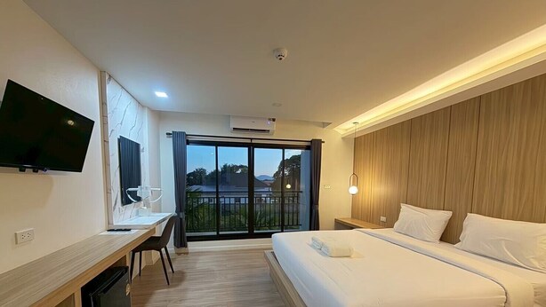 A hotel room with a bed, desk, TV, and a balcony with a view. - The Room Premium Hotel Chiangrai  (Chiang Rai)