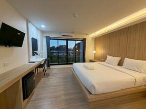 Ein Hotelzimmer mit Bett, Schreibtisch, Fernseher und einem Balkon mit Blick.