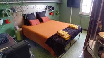 Un dormitorio pequeño con cama, mesita de noche y una ventana.