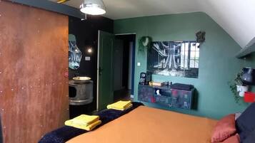 A room with a bed, a table with yellow towels, a coffee machine, and a wall-mounted TV.