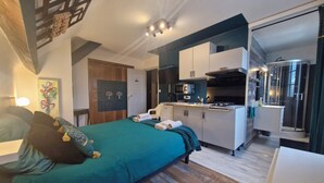 A modern hotel room with a bed, a kitchenette, and a shower area. - L'usine à rêves (Saint-Germain-du-Corbeis)