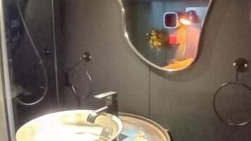 Un baño de diseño moderno, con un espejo grande, un lavabo de acero inoxidable y un inodoro.