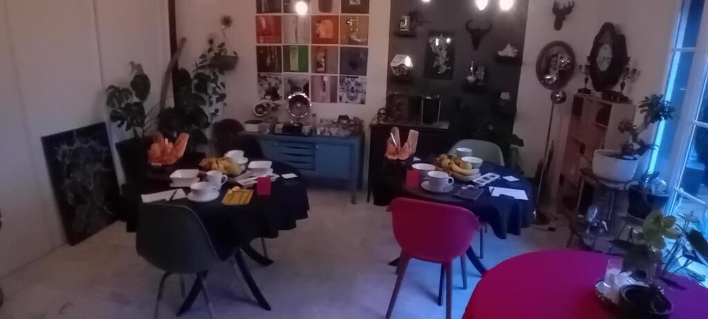 Un coin repas avec une table bleue, des chaises rouges, ainsi que différents plats et ustensiles.