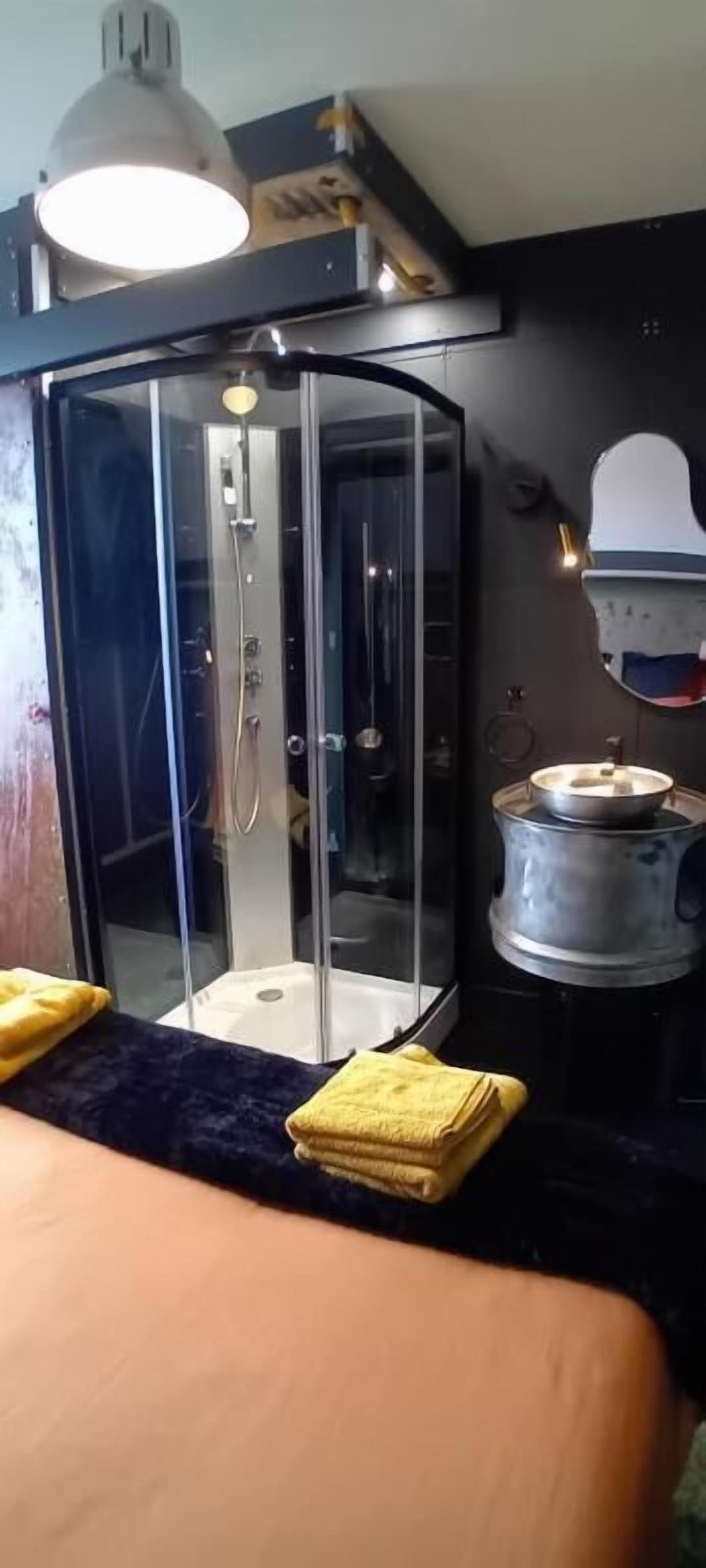 A modern bathroom with a glass-enclosed shower, a sink, and a stove.
