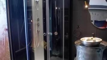 A modern bathroom with a glass-enclosed shower, a sink, and a stove.