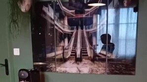 A room with a green wall, a large framed picture of a staircase, a coffee machine, and a shelf with various items. - L'usine à rêves (Saint-Germain-du-Corbeis)