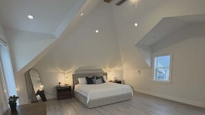Un espacioso dormitorio en el ático con una cama grande, un escritorio y una mesa de comedor.
