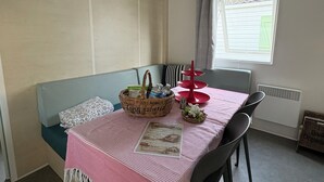 Een kamer met een bed, een tafel met een roze tafelkleed, een stoel, een raam met gordijn en een airconditioning op de muur.