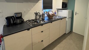 Een kleine keuken met een fornuis, magnetron en een kleine koelkast.