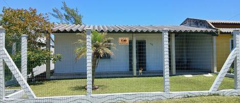 A fenced property with a metal gate, a sign indicating an SOS service, and a number 136 on the building.