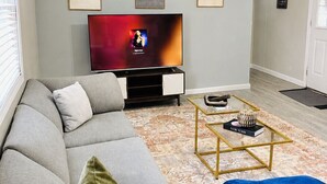 Una sala de estar con un sofá gris, un televisor y una mesa de centro con un libro y un adorno.