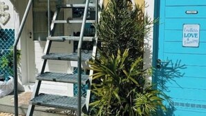 Eine Treppe führt zu einem Gebäude mit einer blauen Tür, einem Blumentopf und einer herzförmigen Dekoration an der Wand.