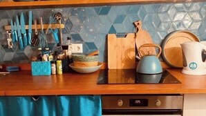Eine Küche mit Holzarbeitsplatte, blauer Fliesenfassade und verschiedenen Küchengeräten und Utensilien.
