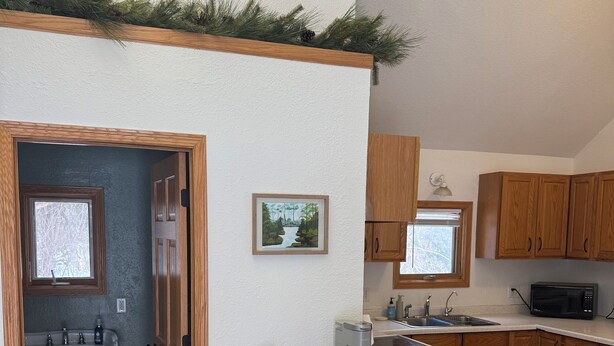 A modern kitchen with wooden cabinets, a built-in island, a sink, and a microwave. - Pet Friendly EAA Rental (Pickett)