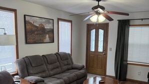 A living room with a sectional sofa, a coffee table, a rug, and a ceiling fan. - Pet Friendly EAA Rental (Pickett)