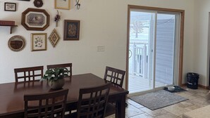 A dining area with a wooden table and chairs, a potted plant, and various framed pictures on the wall. - Pet Friendly EAA Rental (Pickett)
