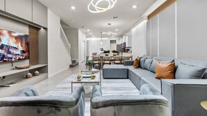 Un salon moderne avec un grand téléviseur à écran plat, un canapé gris et une table basse.