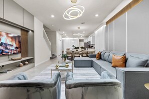 A modern living room with a large flat-screen TV, a grey sofa, and a coffee table. - 5BR house sleeps 16 with game room (Clermont)