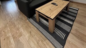 A modern living room with a black sofa, a wooden coffee table, and a black and white striped rug.