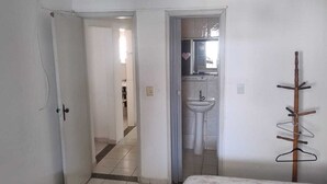 A bedroom with a bed, a ceiling fan, a bathroom with a sink, and a coat rack. - Complete House with Private Pool and BBQ | Praia Grande (Praia Grande)