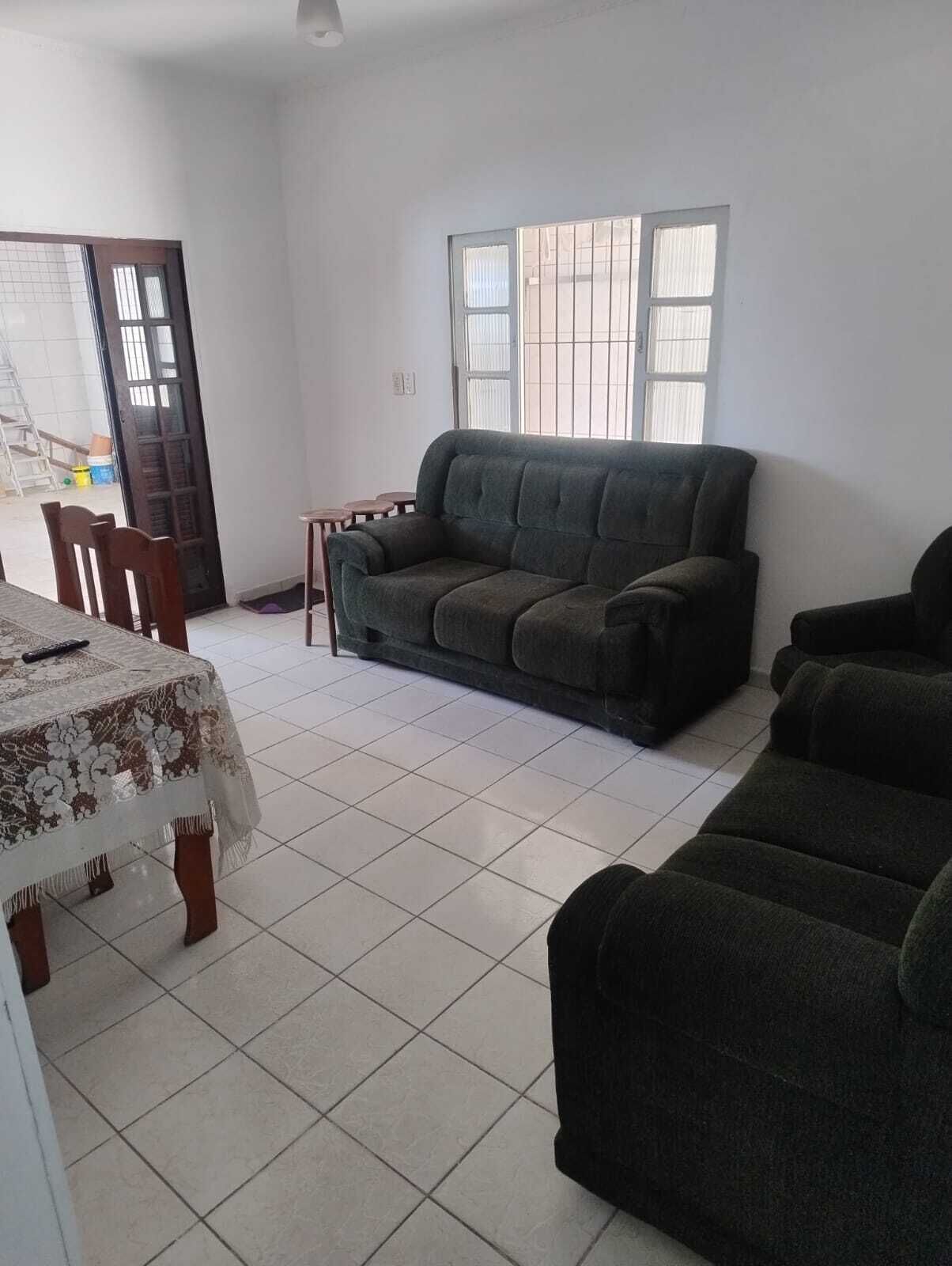 A living room with a sofa, a dining table with chairs, and a window with bars.