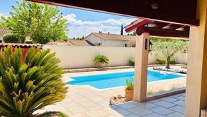 Un'area esterna coperta con piscina, piante in vaso e vista sugli edifici circostanti.