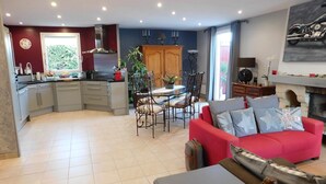 Una cucina moderna con mobili grigi, un divano rosso e un'area pranzo con tavolo e sedie.