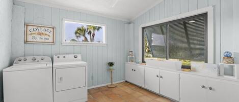 Un lavadero con ventilador de techo, ventana con persianas y un letrero que dice 'COTTAGE By the sea'.