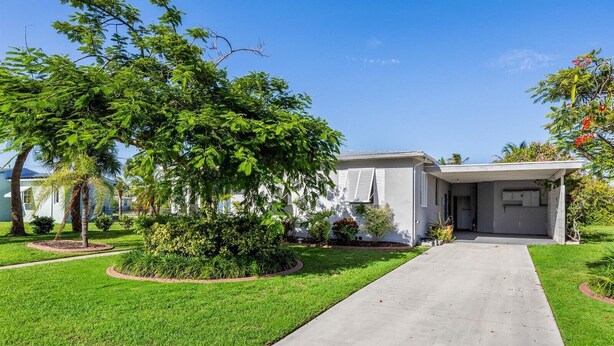 A residential house with a front yard, a driveway, and a garage. - Right Direction Rentals Beachcomber's Retreat (Fort Pierce)