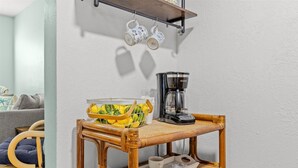 A small wooden table with a coffee maker, a basket of lemons, and a tray with cups and saucers. - Right Direction Rentals Beachcomber's Retreat (Fort Pierce)