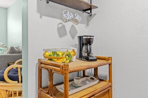 A small wooden table with a coffee maker, a basket of lemons, and a tray with cups and saucers. - Right Direction Rentals Beachcomber's Retreat (Fort Pierce)