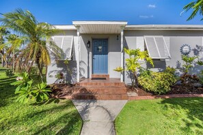 A two-story house with a blue front door, a small front porch, and a brick pathway leading to the entrance. - Right Direction Rentals Beachcomber's Retreat (Fort Pierce)