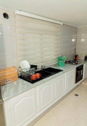 A modern kitchen with a black sink, white cabinets, and a marble countertop. - Enjoy an unforgettable stay in this bright apartment with terrace (Mahdia)